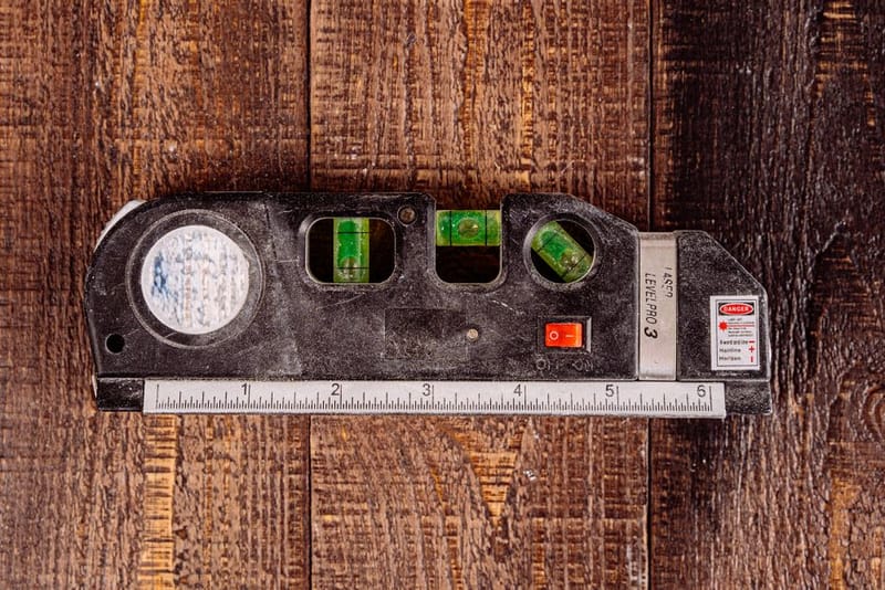 Laser level with spirit vials and a built-in tape measure on a workbench